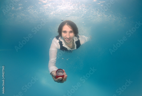 Groom presenting ring, underwater wedding in pool photo