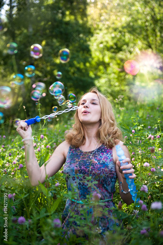 Young girl in the forest playing with soap bubbles
