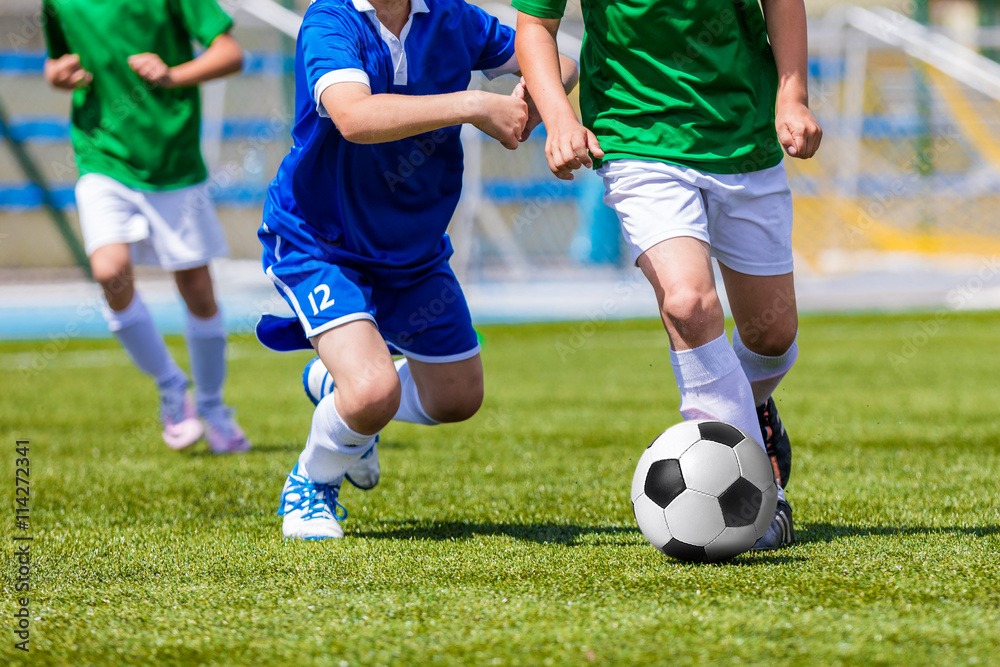 Young boys kicking soccer football on the sports field. Youth blue and green teams tournament competition