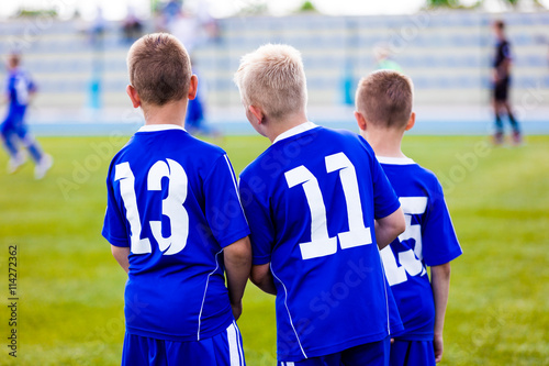 Young soccer team. Reserve players standing together and watching football soccer tournament match for youth teams. Sports background.