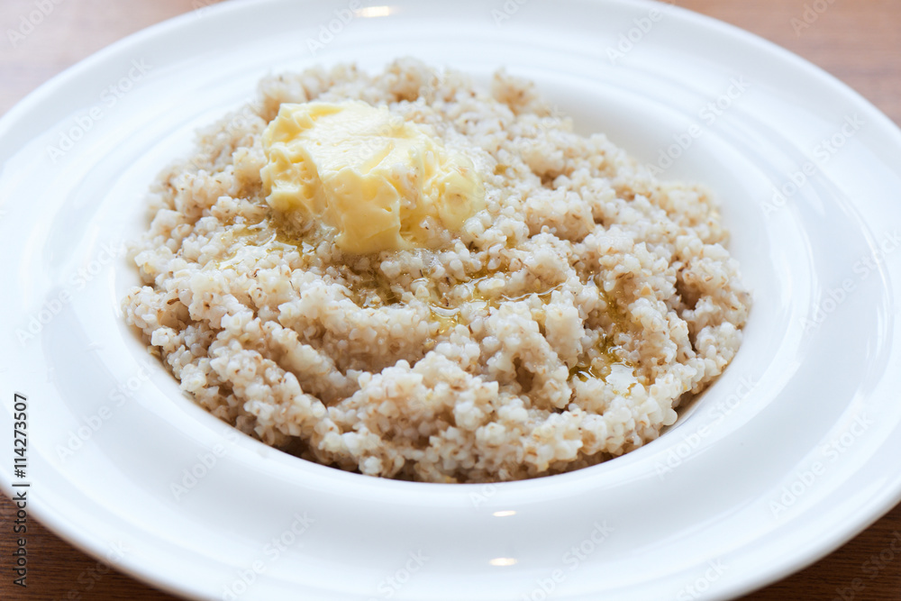 A healthy Breakfast of barley porridge with butter served in a white plate A healthy Breakfast of barley porridge with butter served in a white plate