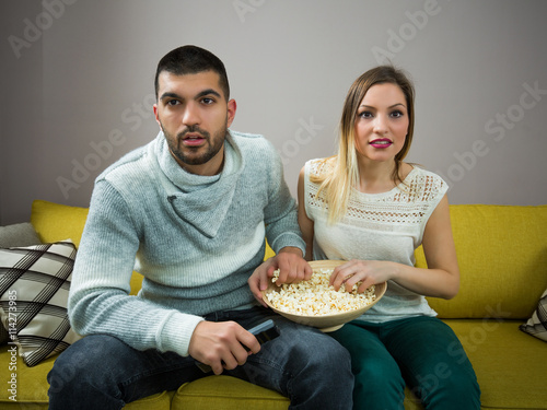 Couple with popcorn watching movie at home