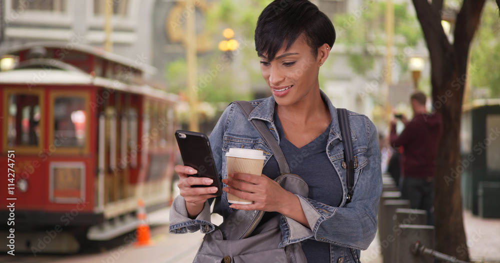 Black woman pulling smartphone out of purse while waiting for tr Black woman pulling smartphone out of purse while waiting for tr
