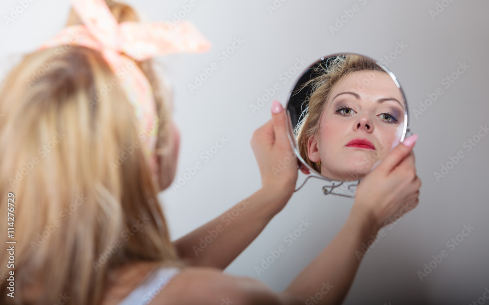 Naklejka premium Pin up blonde fashion girl looking at mirror