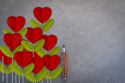 pencil and red heart shape flower on grey background photo