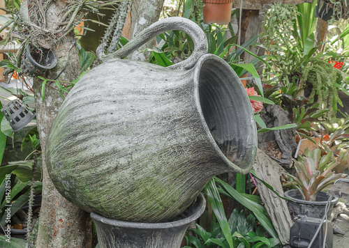 Old big earthen jar for water which has thallophytic plant cling, big water jar shaped like a glass in the garden photo