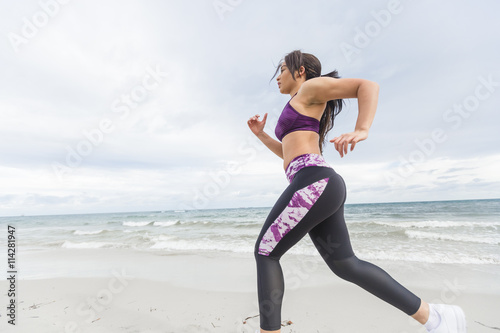 Female runner jogging during outdoor workout on the beach