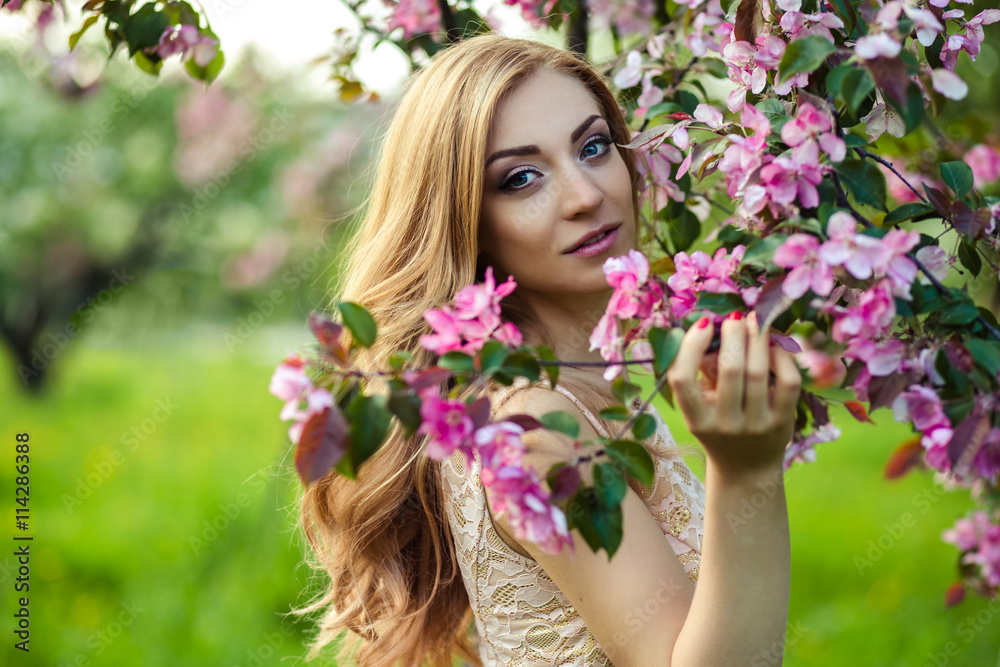 beautiful young woman in a summer dress near blooming trees beautiful young woman in a summer dress near blooming trees