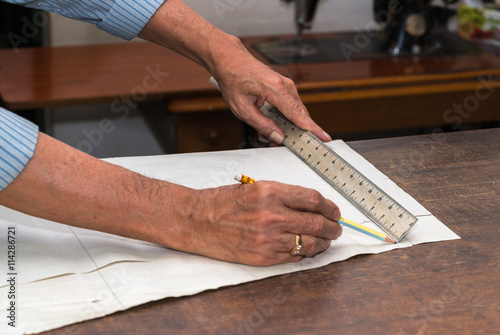 dressmaker drawing tailor pattern with pencil for a suit on the table 