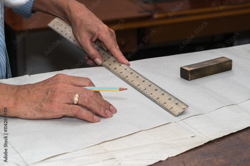 Obraz premium dressmaker drawing tailor pattern with pencil for a suit on the table 