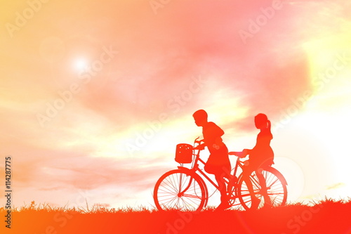 Silhouette children and bicycle at sunset