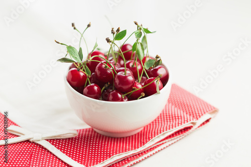 Freshly Picked Cherries With Stem And Leaves In A White Bowl photo