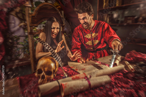 Medieval inquisitor is tempting witch to sign the confession. photo