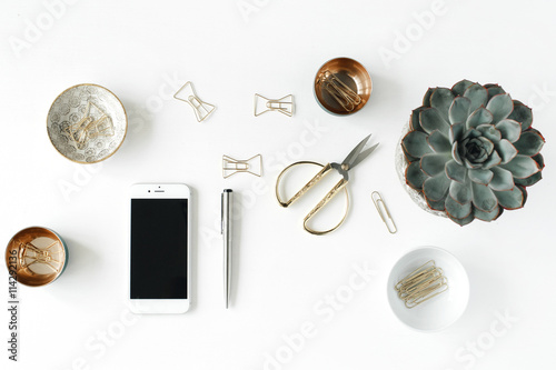 feminini desk workspace with succulent, phone, scissors and golden clips on white background. flat lay, top view photo