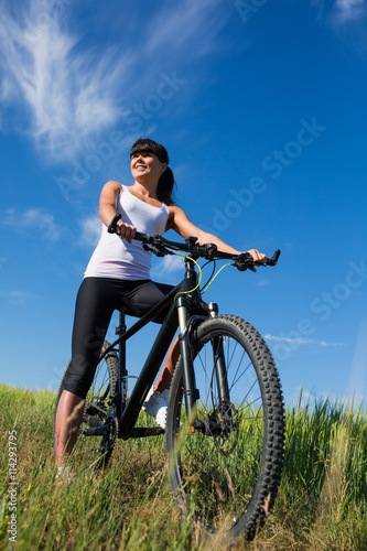 Sport bike woman on the meadow with a beautiful landscape