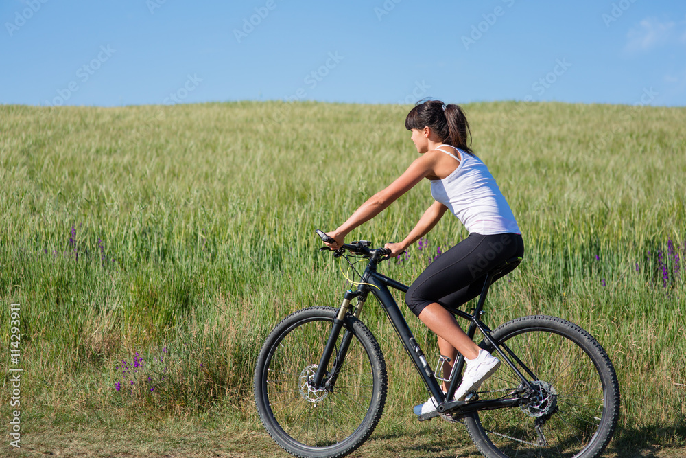 Sport bike woman on the meadow with a beautiful landscape