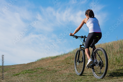 Sport bike woman on the meadow with a beautiful landscape