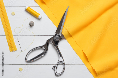 Cutting textile or fine cloth with a tailor scissors on wooden t
