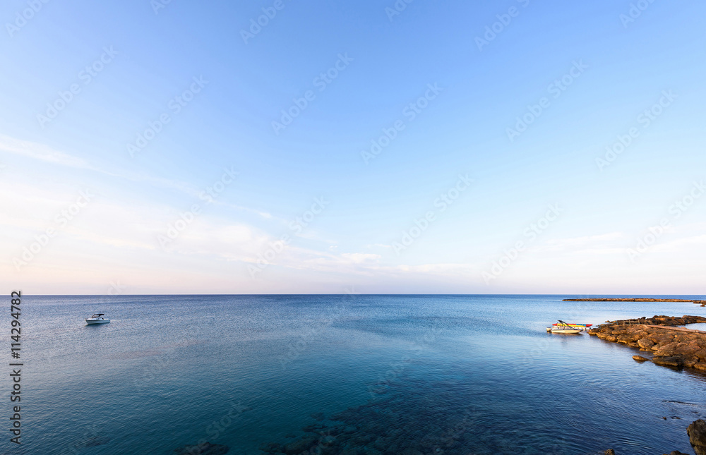 Fototapeta premium Photo of sea in protaras with rocks, cyprus island with boats at sunset.