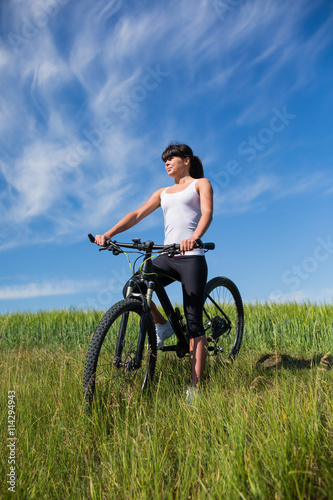 Sport bike woman on the meadow with a beautiful landscape © Aleksey