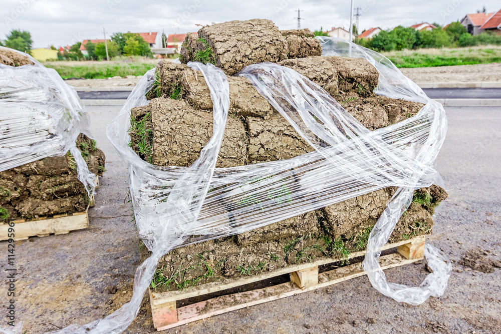 Pallet of sod rolls are wrapped in foil, unrolling grass