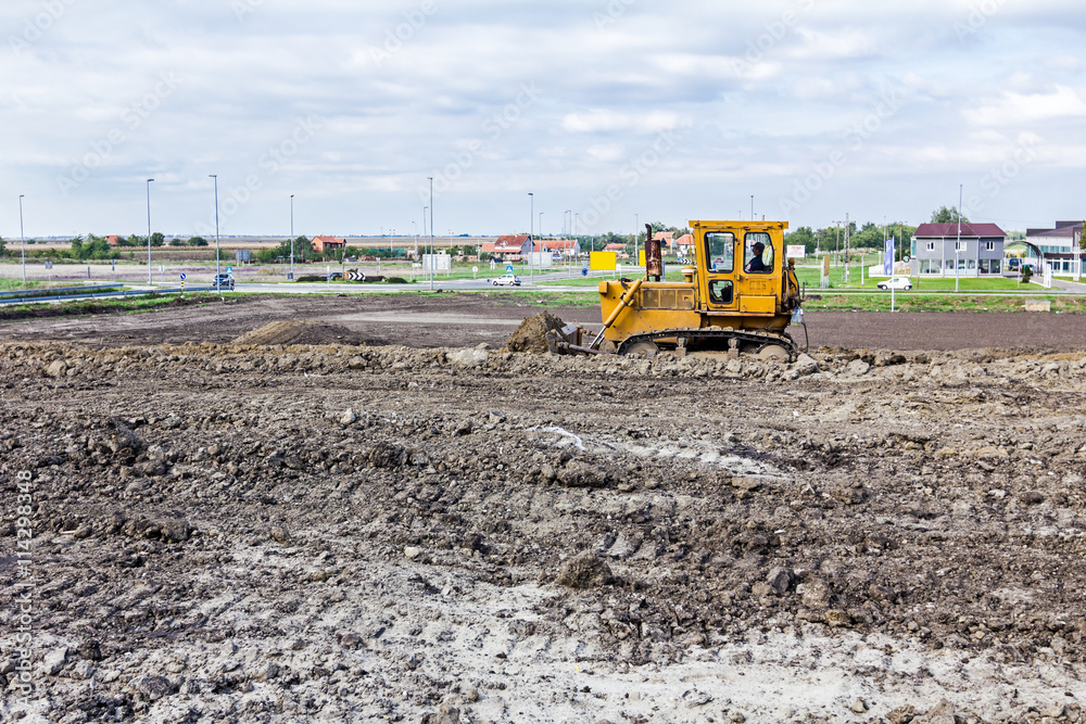 Obraz premium Bulldozer machine is leveling construction site