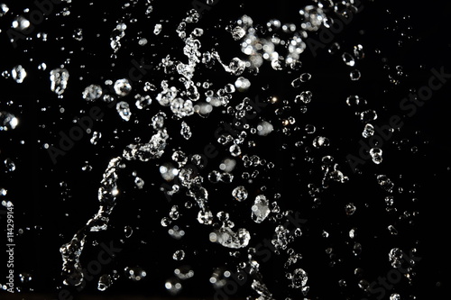 Water drops fly in the air with defocused lights on background