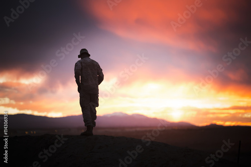 The military stands on the rock on sunset background