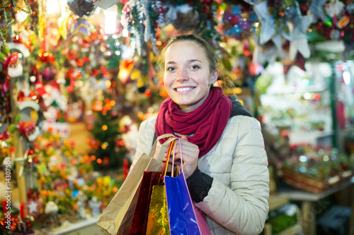 woman choosing Christmas decoration at market in evening time