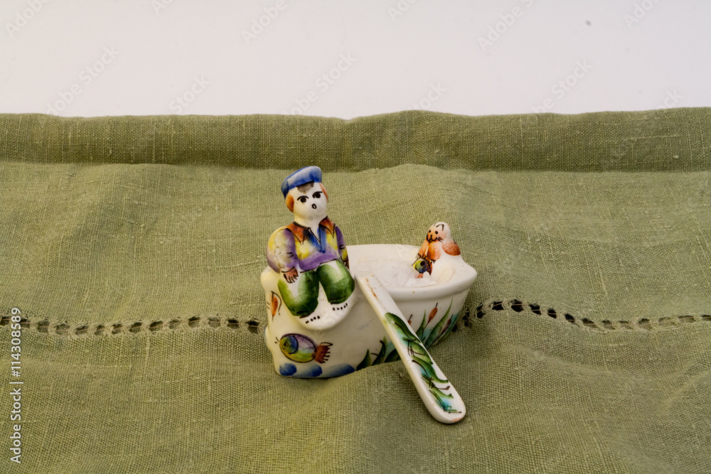 Fototapeta premium Open castor in Russian primitive style with figures of man and cat on green linen tablecloth.