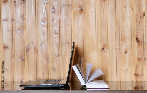 Book and Laptop on a wooden table. Wood background. E-learning.