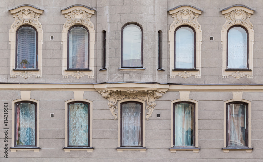 Several windows in a row and bay window on facade of urban apartment building front view, St. Petersburg, Russia.