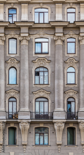Several windows in a row and balcony on facade of urban apartment building front view, St. Petersburg, Russia.