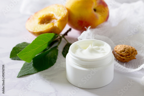 Face cream with peach on a gray stone background - beauty salon.