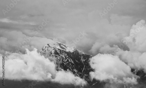 Snowy peak of the mountain shrouded in thick clouds.Black and white photo
