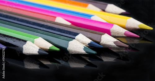 collection of sharp color pencils with reflection on black background