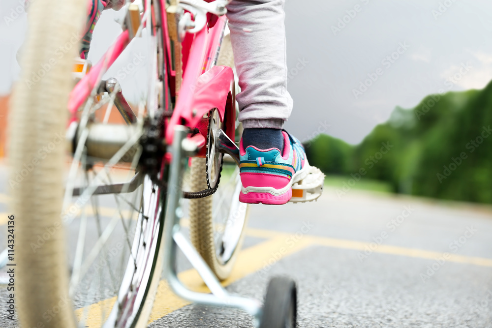 Naklejka premium Nice little girl riding her bike on a road