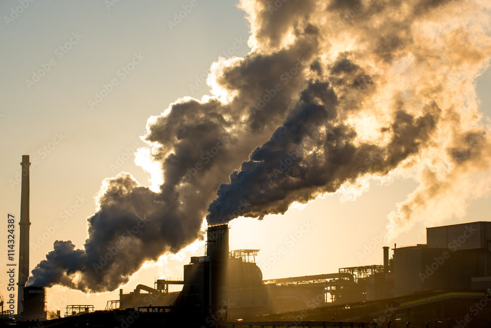 Sunset at steel factory showing smoke chimneys