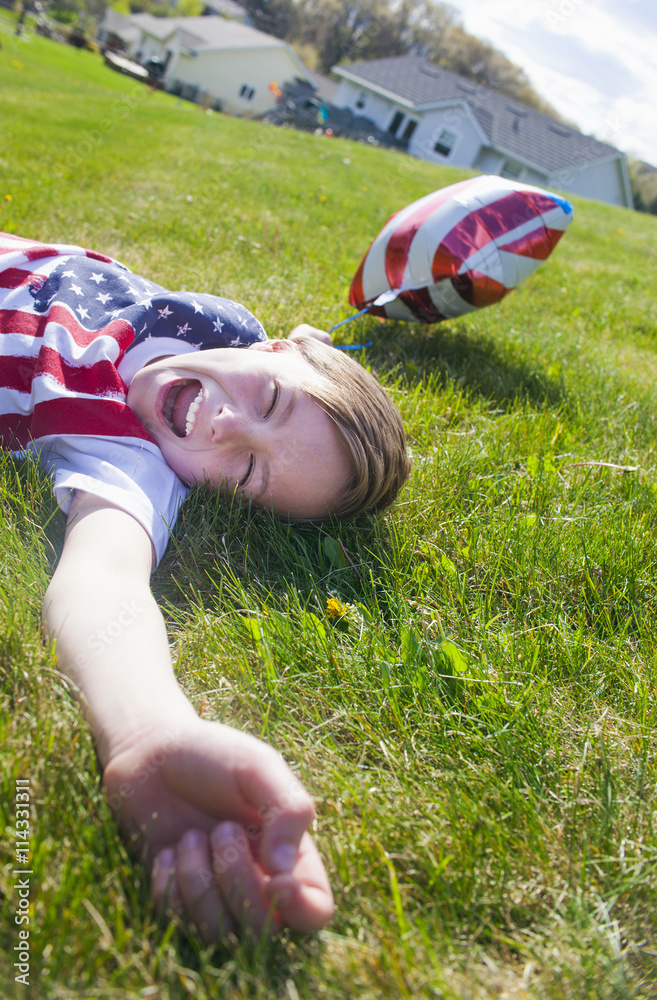 Cheerful boy lying on green grass. 4th of July. Independence day. Cheerful boy lying on green grass. 4th of July. Independence day.