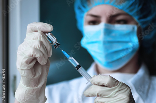 health worker dials the vaccine into a syringe photo