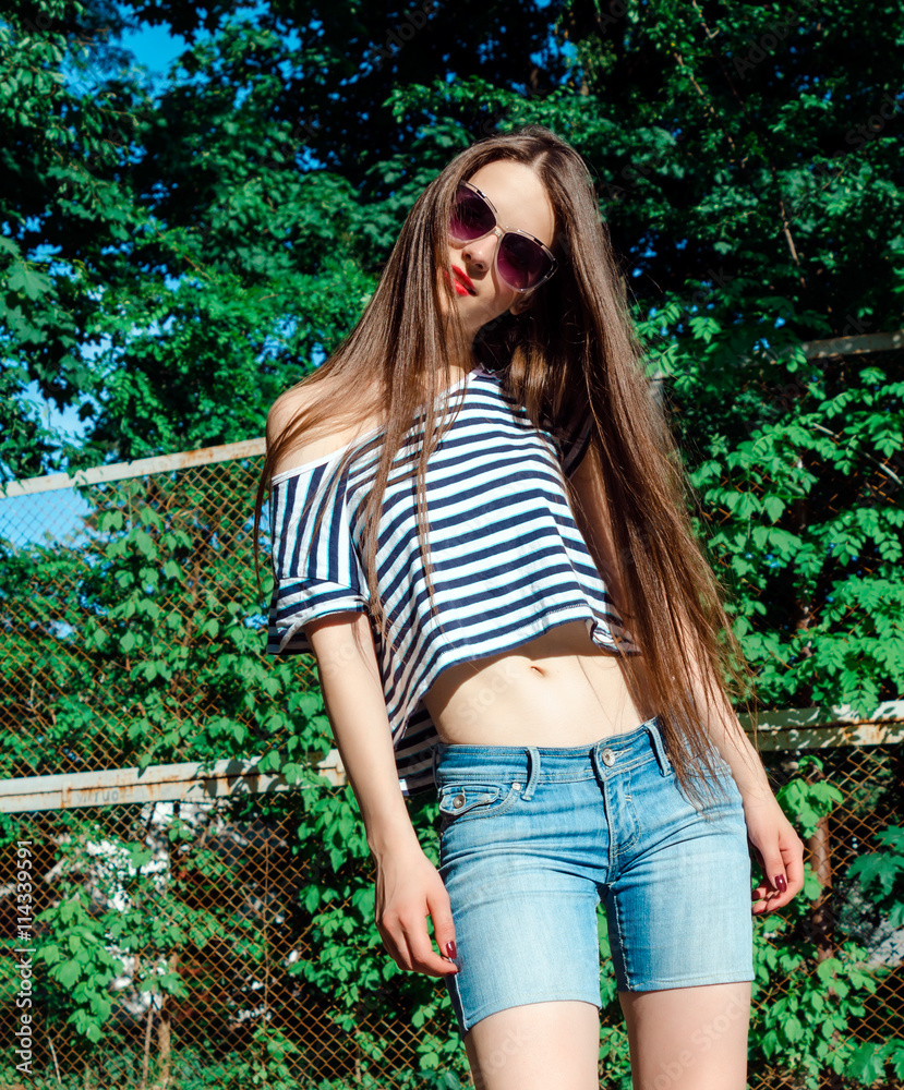 Young female model outdoor portrait wearing striped shirt and denim shorts.  Fashion lady with long brown hair wear cool outfit and high heels Photos |  Adobe Stock