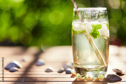 Fresh mint drink with ice in a glass on  a wooden table