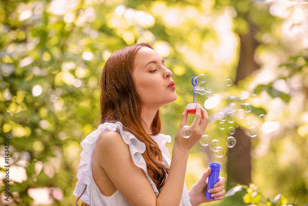 Beautiful girl blowing bubbles in park Beautiful girl blowing bubbles in park