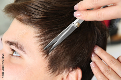 Professional hairdresser making stylish haircut, closeup