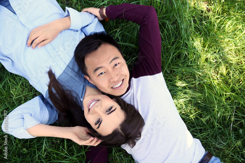 Happy couple lying on green...