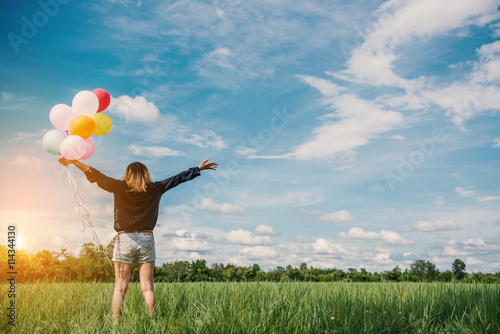 young asian woman on green grassland with colored balloons in thailand