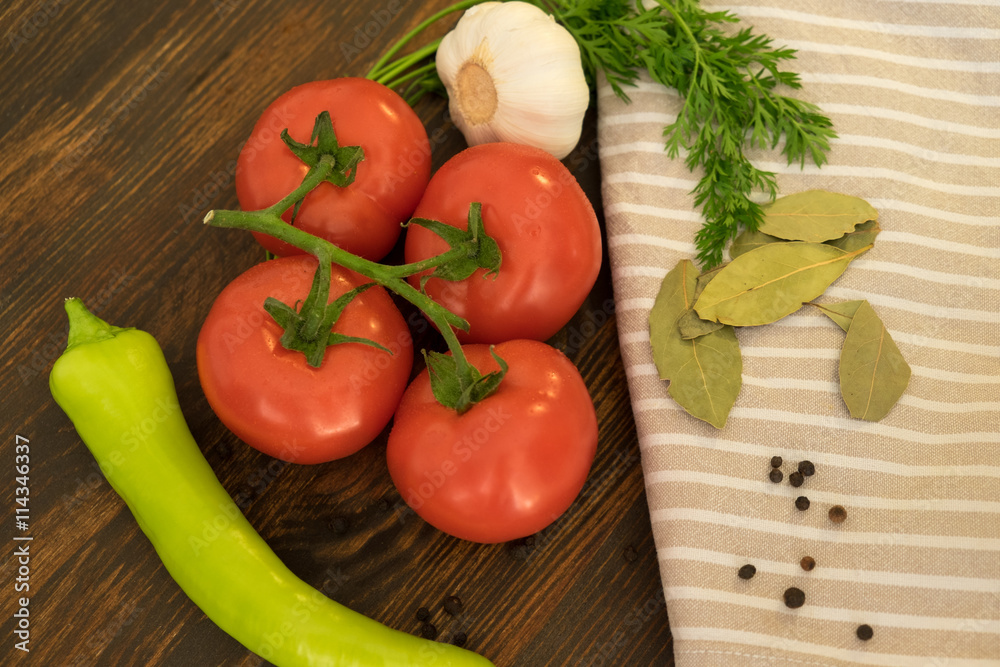 Top view of tomato, garlic, pepper, bay leaf and spices on dark wood background