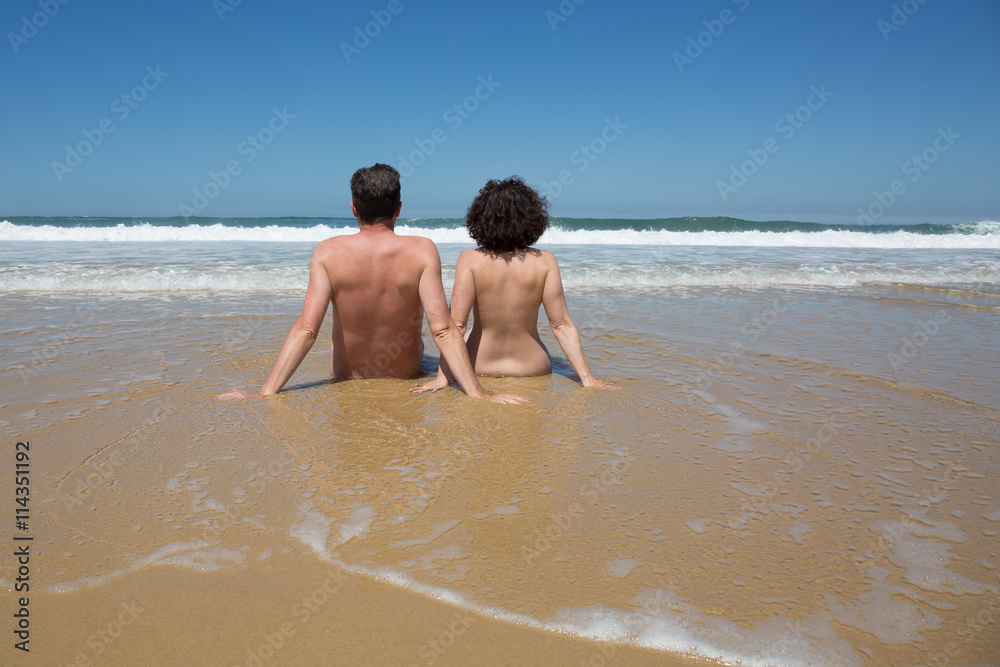 Naked couple sitting on the beach, summertime Naked couple sitting on the beach, summertime