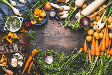 Vegetables cooking ingredients for tasty vegetarian dishes. Carrot , potato , onion , mushrooms , garlic , thyme , parsley on dark rustic wooden background, frame