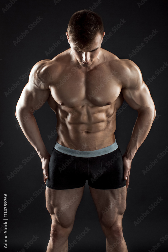 Fototapeta premium Muscular bodybuilder guy doing posing over black background